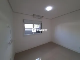 Uma sala de estar ampla e clara com piso de porcelanato e janela.