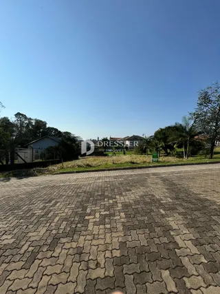 Vista externa da propriedade com pavimento de paralelepípedos e vegetação.