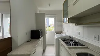 Uma cozinha moderna com armários brancos e bancadas claras.
