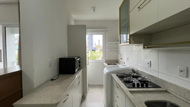 Uma cozinha moderna com armários brancos e bancadas claras.