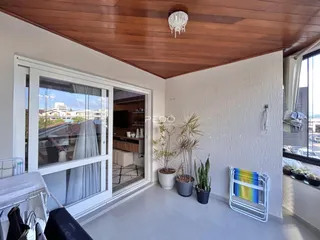 Ambiente interno com teto de madeira e portas de vidro que dão acesso a uma área externa.