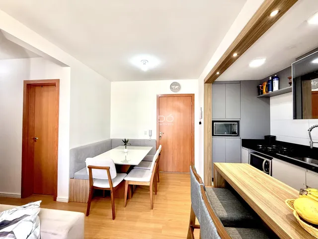 Sala de estar com cozinha integrada e piso de madeira clara.