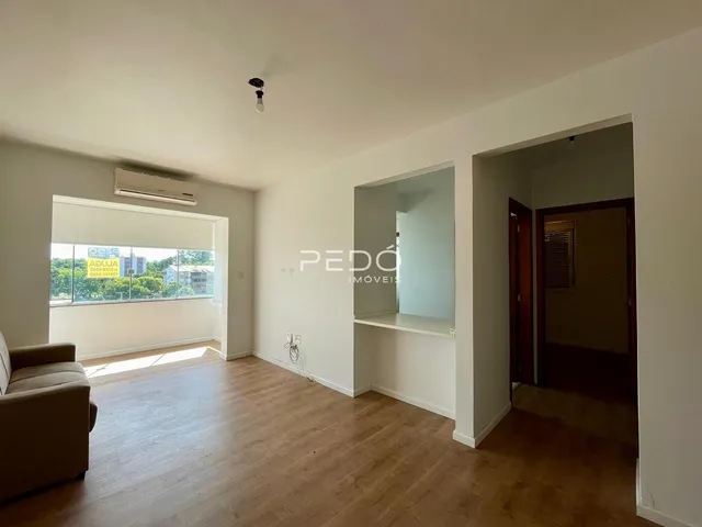 Sala de estar com piso de madeira clara e parede branca.