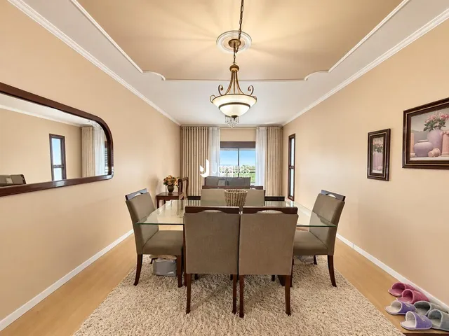 Sala de jantar com mesa de vidro e cadeiras em um ambiente claro.