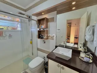Banheiro com box de vidro e bancada de madeira no imóvel.