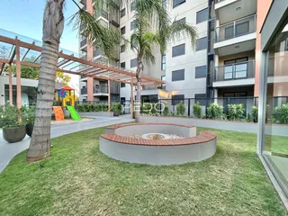 Vista externa de um jardim com pérgola e vegetação em um apartamento em Lajeado.