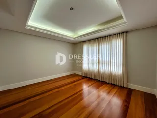 Sala de estar com piso de madeira e cortinas claras.