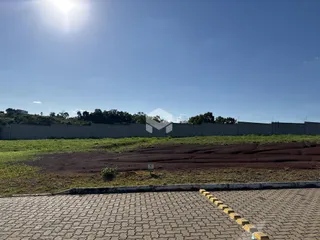Vista externa de uma propriedade com muro e área gramada.