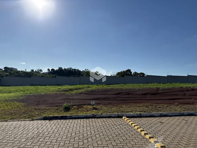 Vista externa de uma propriedade com muro e área gramada.