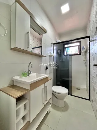Foto de um banheiro moderno com revestimento branco e armários brancos.