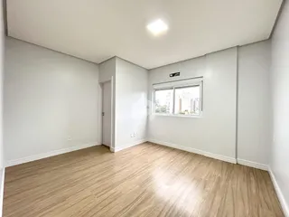 Uma sala de estar com piso de madeira clara e paredes brancas.