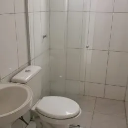 Foto de um banheiro com azulejos brancos e um vaso sanitário.