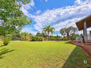 Vista externa de um jardim verde com árvores sob um céu azul.