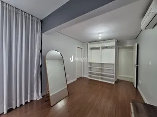 Sala de estar com piso de madeira e armários brancos.