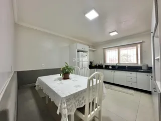 Uma sala de jantar clara com mesa de tecido e ambiente bem iluminado.