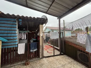 Área externa com cerca e roupas secando ao lado de uma casa.