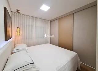 Quarto com cama de casal e cortinas brancas em um imóvel.