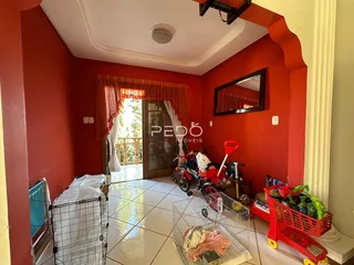 Interior de uma sala com paredes vermelhas e piso de cerâmica clara.