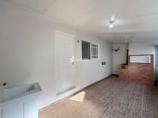 Vista interna de um corredor com piso de cerâmica e parede de tijolo aparente.