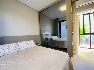 Quarto com cama e porta de vidro refletindo outro quarto.