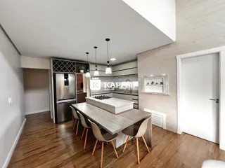Uma sala de jantar moderna com mesa de madeira e cozinha visível.