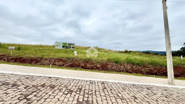 Vista da propriedade com gramado e área pavimentada na frente.