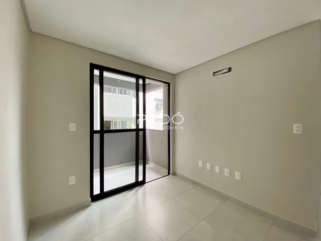 Interior de uma sala com porta de vidro que se abre para outra área.