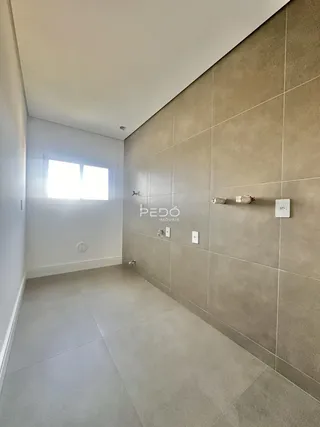 Corredor interno com paredes de azulejo claro e piso liso.
