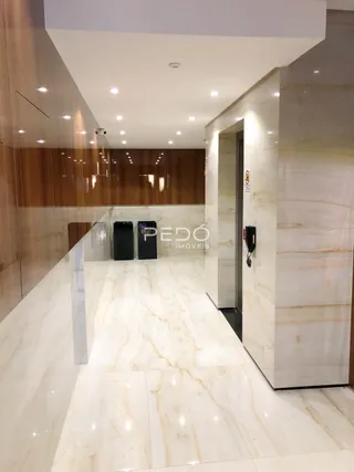 Corredor interno com piso de mármore claro.