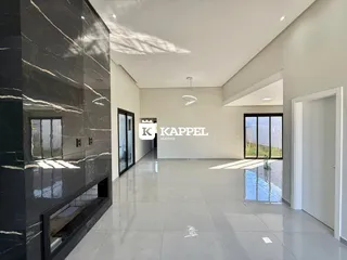 Ambiente interno amplo com piso claro e parede de mármore escura.