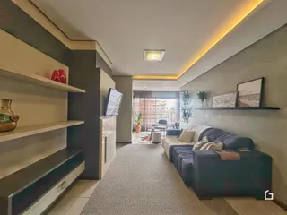 Sala de estar moderna com estantes e sofá em um apartamento no Brasil.