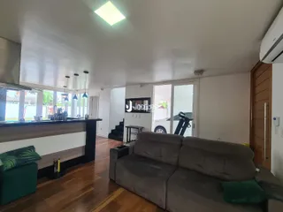 Sala de estar com piso de madeira e grandes janelas.