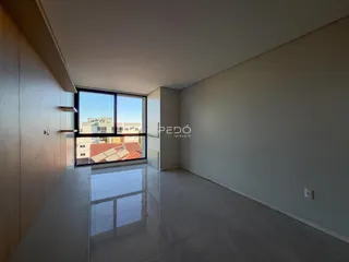Vista interna de um ambiente com piso claro e grande janela.