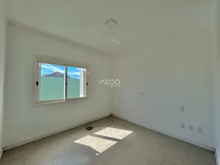 Ambiente interno de uma sala com grande janela e vista para a paisagem.