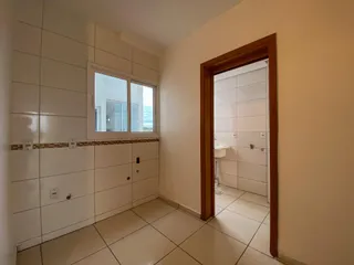 Uma foto de um corredor interno com paredes brancas e piso de cerâmica.