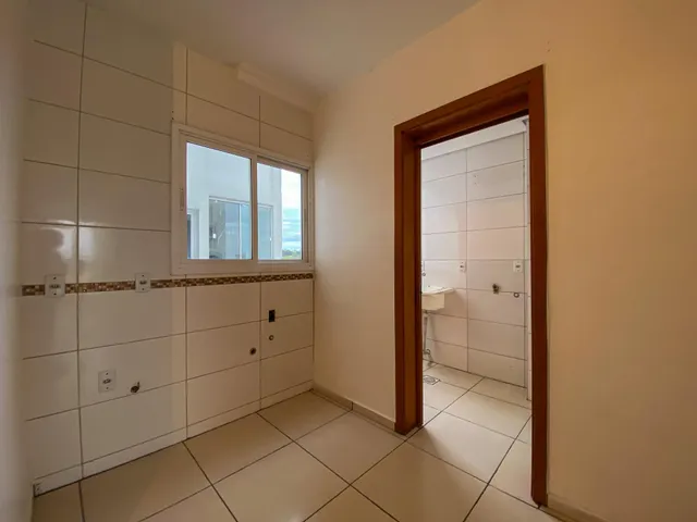 Uma foto de um corredor interno com paredes brancas e piso de cerâmica.