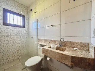 Banheiro com bancada de granito e revestimento de azulejos brancos.
