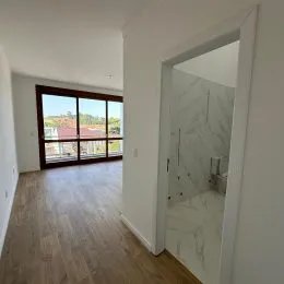 Hall de entrada com piso de madeira clara e passagem para um cômodo.