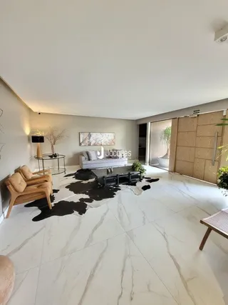 Sala de estar ampla com piso claro e paredes brancas.