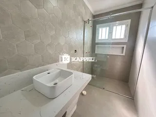 Foto de um banheiro com bancada de mármore e box de vidro transparente.