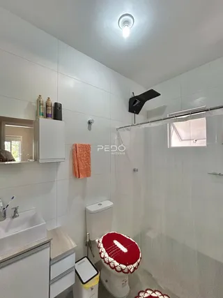 Banheiro moderno com revestimento branco e box de vidro.