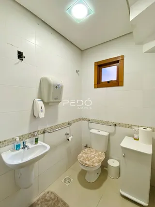 Banheiro com louças sanitárias brancas e revestimento de azulejos