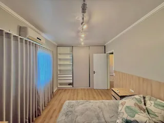 Quarto com cama e armários brancos e piso de madeira clara.