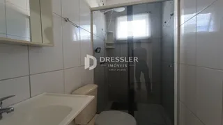 Foto de um banheiro com revestimento branco.