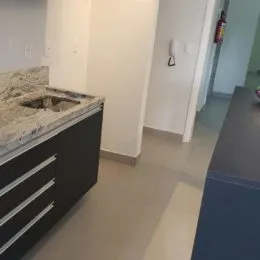 Vista parcial de um balcão de cozinha com armários escuros em um ambiente interno.