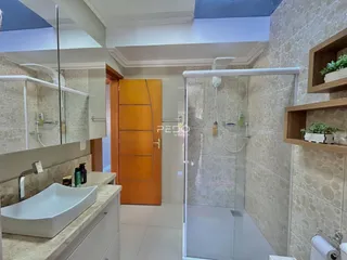 Foto de um banheiro com box de vidro e revestimento de cerâmica.