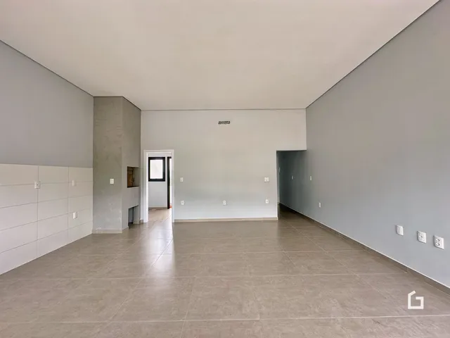 Ambiente interno amplo com paredes brancas e piso de cerâmica.