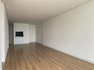 Sala ampla com piso de madeira clara e paredes brancas.