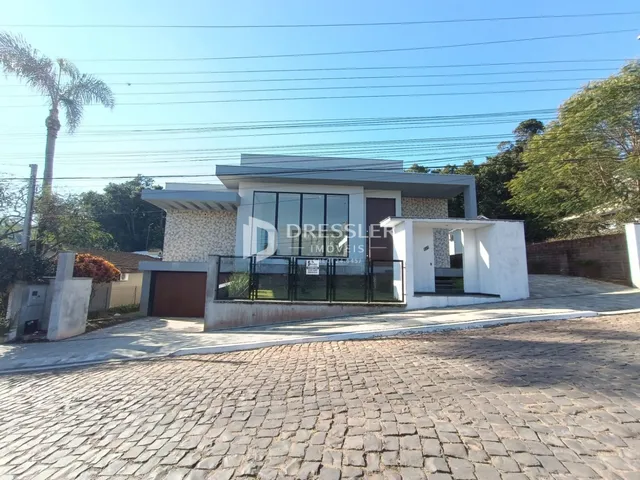 Fachada de uma residência moderna em Lajeado, Brasil, com garagem e muro frontal.