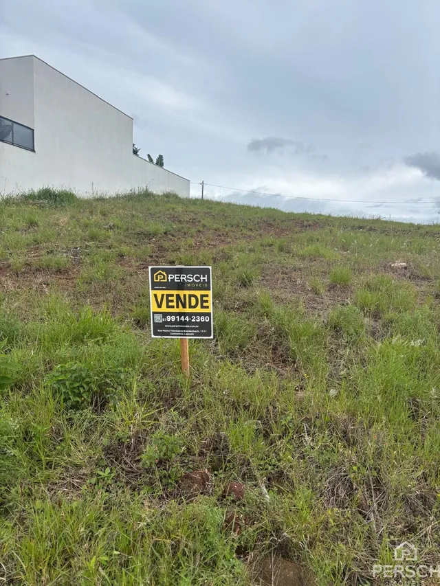 Vista externa de um edifício branco com grama alta no primeiro plano.